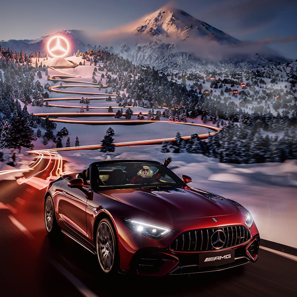 Mercedes-AMG SL driving down a snowy mountain road toward an illuminated Mercedes star